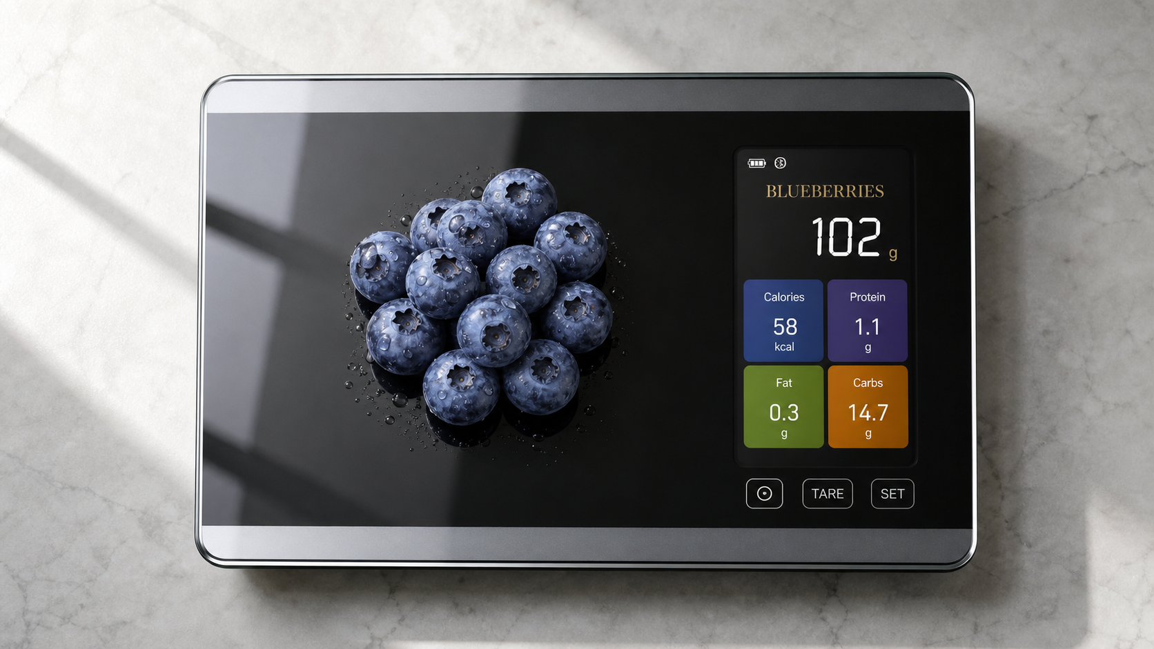 Black tempered-glass WellMall voice kitchen scale on a marble kitchen counter showing weight and nutrition data on its color display, a hand placing blueberries on the weighing platform